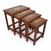 Set of four wooden nesting tables with decorative tops on a white background