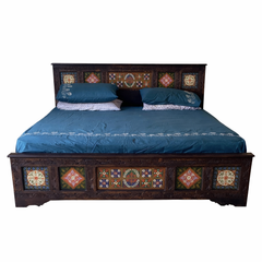 Decorative bed with intricate wooden headboard and footboard on a white background